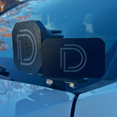 Black Diode Dynamics logo pod light covers mounted on a blue truck